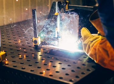man welds at the factory working in metal industry